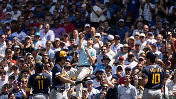 A fan climbs the netting at Wrigley Field to retrieve a bat.